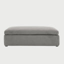 Vista frontal del taburete Marie en color gris, con un diseño rectangular alargado, cojín superior de gran espesor y base tapizada liza que llega casi al nivel del suelo.