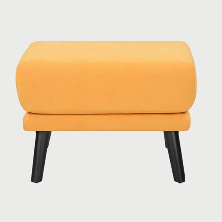 Vista frontal del taburete San Blas en color amarillo, con un asiento de cojín grueso y cuadrado con bordes redondeados, sobre cuatro patas cónicas de madera en acabado negro.