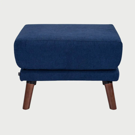 Vista frontal del taburete San Blas tapizado en tela azul, con un asiento de cojín cuadrado de gran espesor y patas cónicas de madera en acabado nogal oscuro.