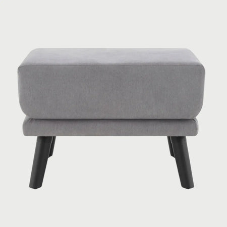 Vista frontal del taburete San Blas en color gris, con un asiento de cojín cuadrado de gran espesor y patas cónicas de madera en acabado negro mate.