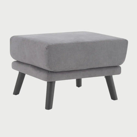 Vista lateral del taburete San Blas gris, resaltando el perfil robusto del acolchado y la inclinación de las patas negras que brindan una base estable y moderna.