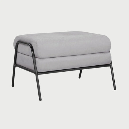 Vista lateral del taburete Tuxama gris, mostrando la profundidad de sus cojines acolchados y el perfil delgado de la estructura metálica que rodea el asiento.